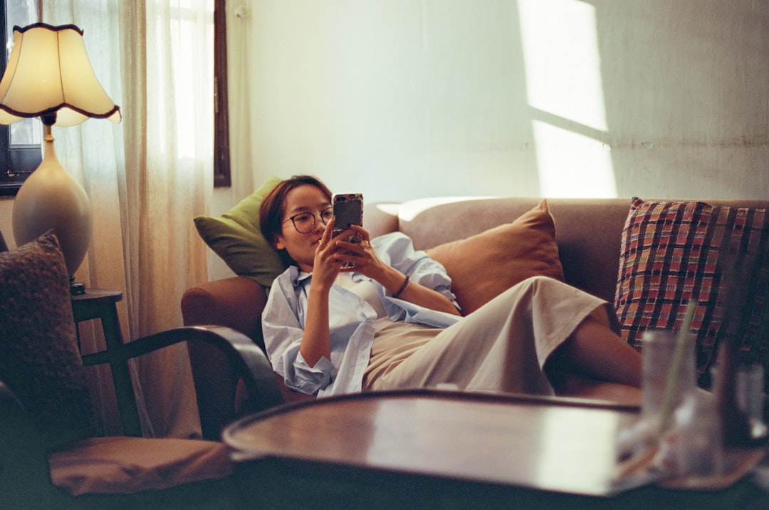 女性が自宅のソファでスマホを使うイメージ